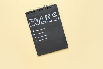 Notebook with blank list of rules on beige background