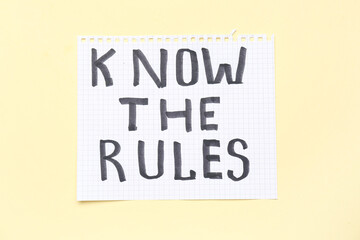 Paper with text KNOW THE RULES on beige background