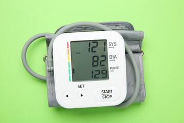 Blood pressure measuring device on green background, top view