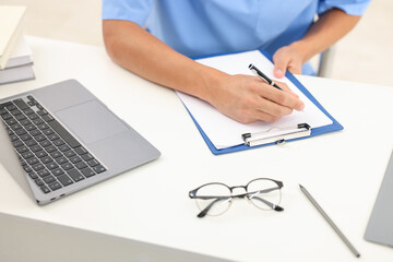 Fototapeta premium Medical student taking notes while studying at table indoors, closeup