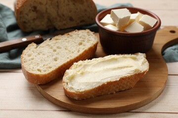 Fresh bread with butter on light wooden table, closeup