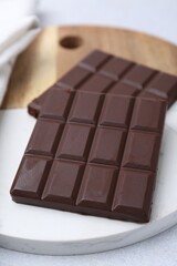 Pieces of delicious dark chocolate bar on light table, closeup