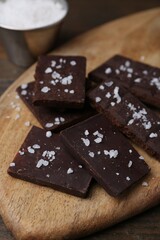 Pieces of chocolate with salt on wooden table, closeup