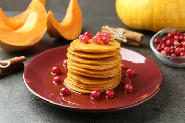 Tasty pumpkin pancakes with cranberries and honey on grey table, closeup