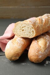Cut fresh baguettes on grey wooden table, closeup
