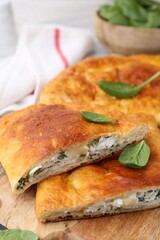 Pieces of tasty calzone with basil and cheese on table, closeup