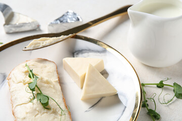 Plate with bread, triangles of tasty processed cheese, micro green and milk on light table, closeup