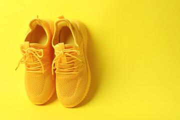 Pair of stylish sneakers on yellow background. Space for text