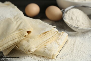 Raw puff pastry dough, eggs and flour on table, closeup