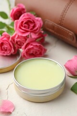 Natural solid perfume in container and pink roses on white table, closeup