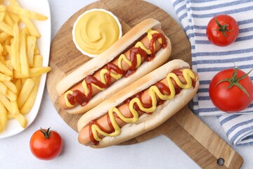 Tasty hot dogs served on light table, flat lay