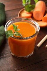 Fresh carrot juice and mint in glass on wooden table, closeup