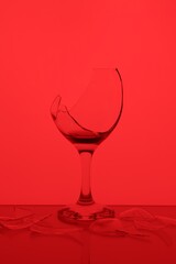 Pieces of broken glass with wine against red background, color tone effect