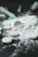 Drug addiction. Powder, pills and syringes on gray table, closeup