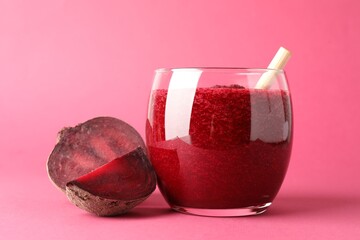 Fresh beetroot smoothie in glass and cut vegetable on pink background, closeup