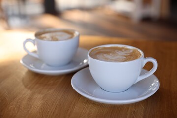 Cups of aromatic coffee on wooden table in cafe, closeup