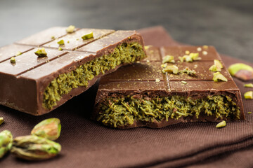 Pieces of tasty Dubai chocolate bar with pistachios and knafeh on table, closeup