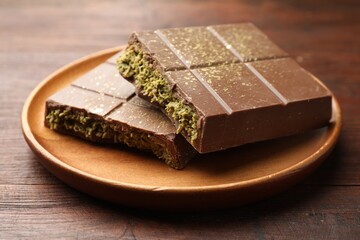 Pieces of tasty Dubai chocolate with pistachios and knafeh on wooden table, closeup