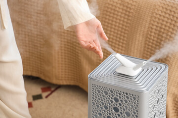 Woman with modern air humidifier in bedroom, closeup