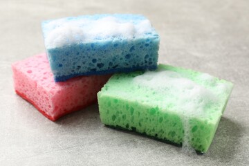 Sponges and foam on light grey table, closeup