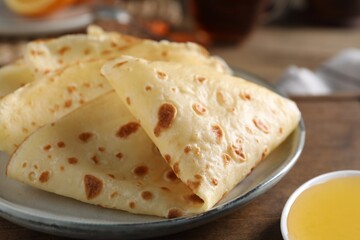 Delicious crepes and honey on wooden table, closeup