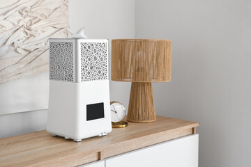 Modern air humidifier with alarm clock and lamp on commode in bedroom