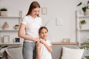 Fototapeta premium Happy mother and her daughter with medical patches after vaccination at home