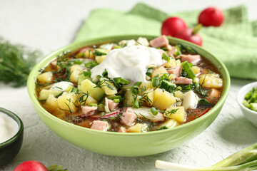 Bowl of tasty okroshka and ingredients on light table