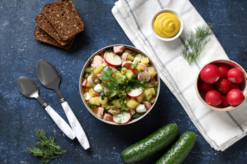 Composition with bowl of tasty okroshka, ingredients, bread and spoons on color background