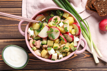 Bowl with tasty okroshka, sour cream and green onion on wooden table