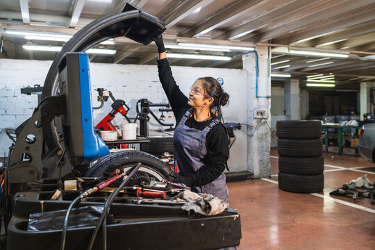 Female chinese mechanic lifting tire in auto repair shop
