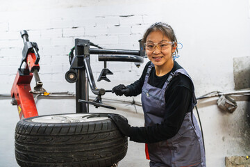 Female chinese mechanic changing car tire in auto repair shop