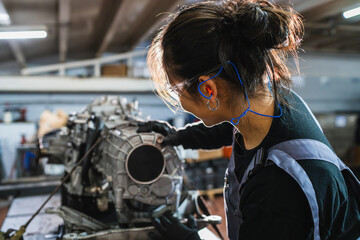 Female mechanic inspecting gearbox in auto repair shop