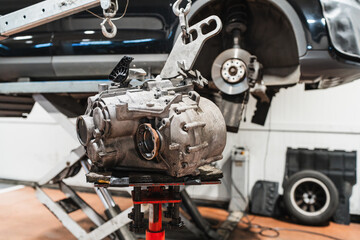 Mechanics replacing car gearbox in auto repair shop