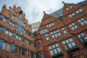 Historic buildings in red brick architecture in Boettcherstrasse in Bremen, Germany with the celebrated carillon or glockenspiel between the gables under a cloudy sky