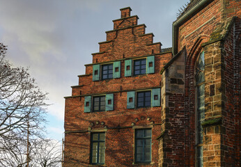 Historic building at the Martini church in Bremen, Germany in red brick architecture with stepped gable and wooden shutters, cloudy sky