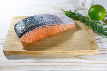 Fresh raw salmon fillet with skin on a kitchen cutting board, cooking a healthy fish meal, selected focus