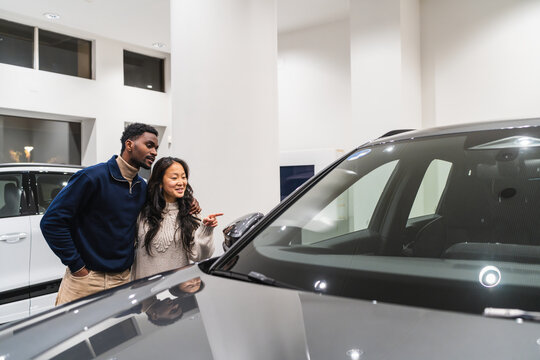 Young couple choosing new car in dealership showroom