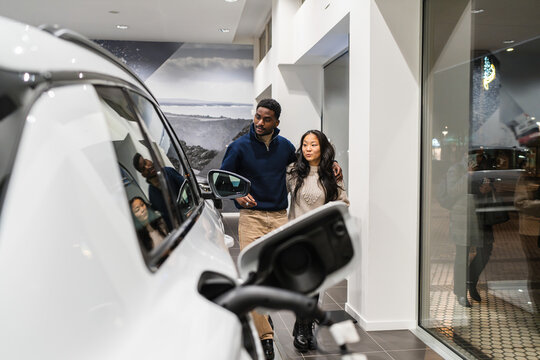 Couple choosing electric car in dealership showroom