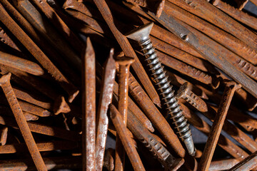 Rusty iron nails piled up in disarray and a new chrome on top