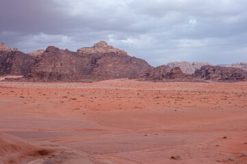 Fototapeta premium A desert landscape with a cloudy sky in the background