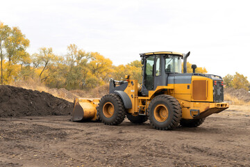 Wheel loader hauling dirt. Front-end loader in a field moving dirt