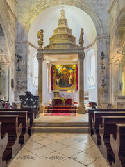 Korcula, Croatia - June 30, 2024: Saint Mark Cathedral. Main altar and chancel with large painting and stone baldaquin and stone angel statues, Dark wooden benches in front © Klodien