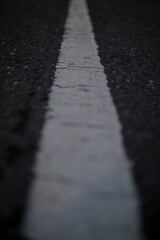 A close-up of a white line painted on a dark asphalt road.