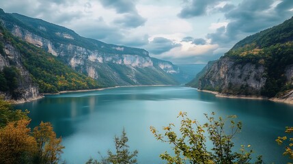 Obraz premium Serene Mountain Lake Landscape. Scenic view of a tranquil alpine lake nestled between towering mountains.