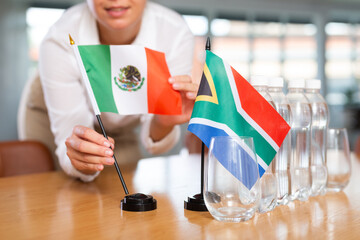 Little flag of South Africa on table with bottles of water and flag of Mexico put next to it by...