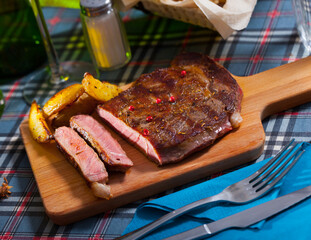 Tasty juicy roasted beef served with roasted potato on wooden board