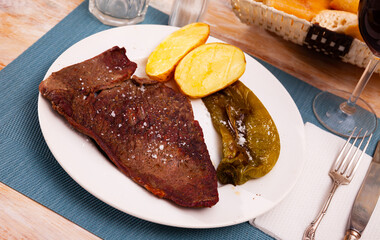 Appetizing grilled beef steak with side dish of potatoes and jalapenos peppers