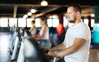 Young athletic man in sportswear training on exercise bike in gym