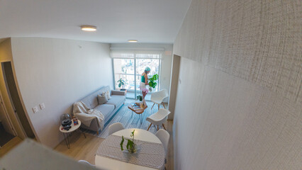 A woman is standing in a living room with a potted plant. New home concept.
